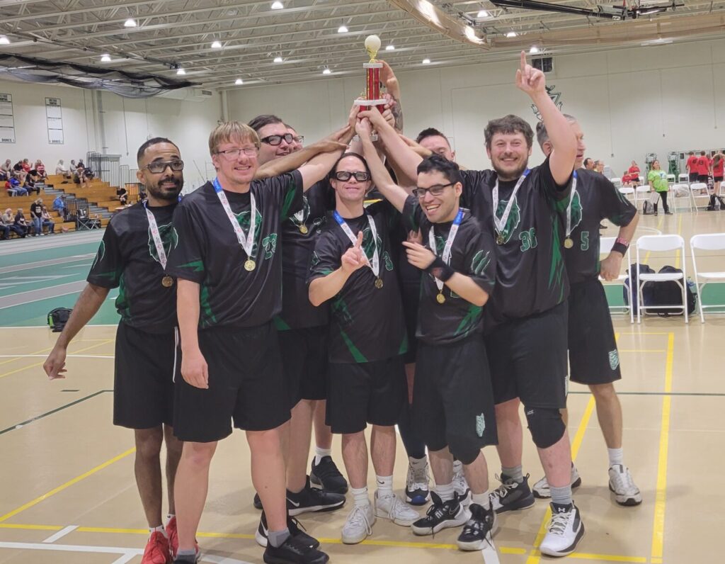 Male basketball team with trophy in gym