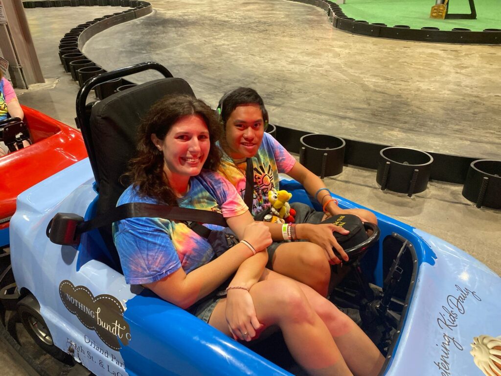 Summer camp boy with female camp staff in a light blue go-cart
