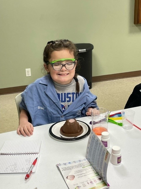 Smiling little girl doing an experiment at a program