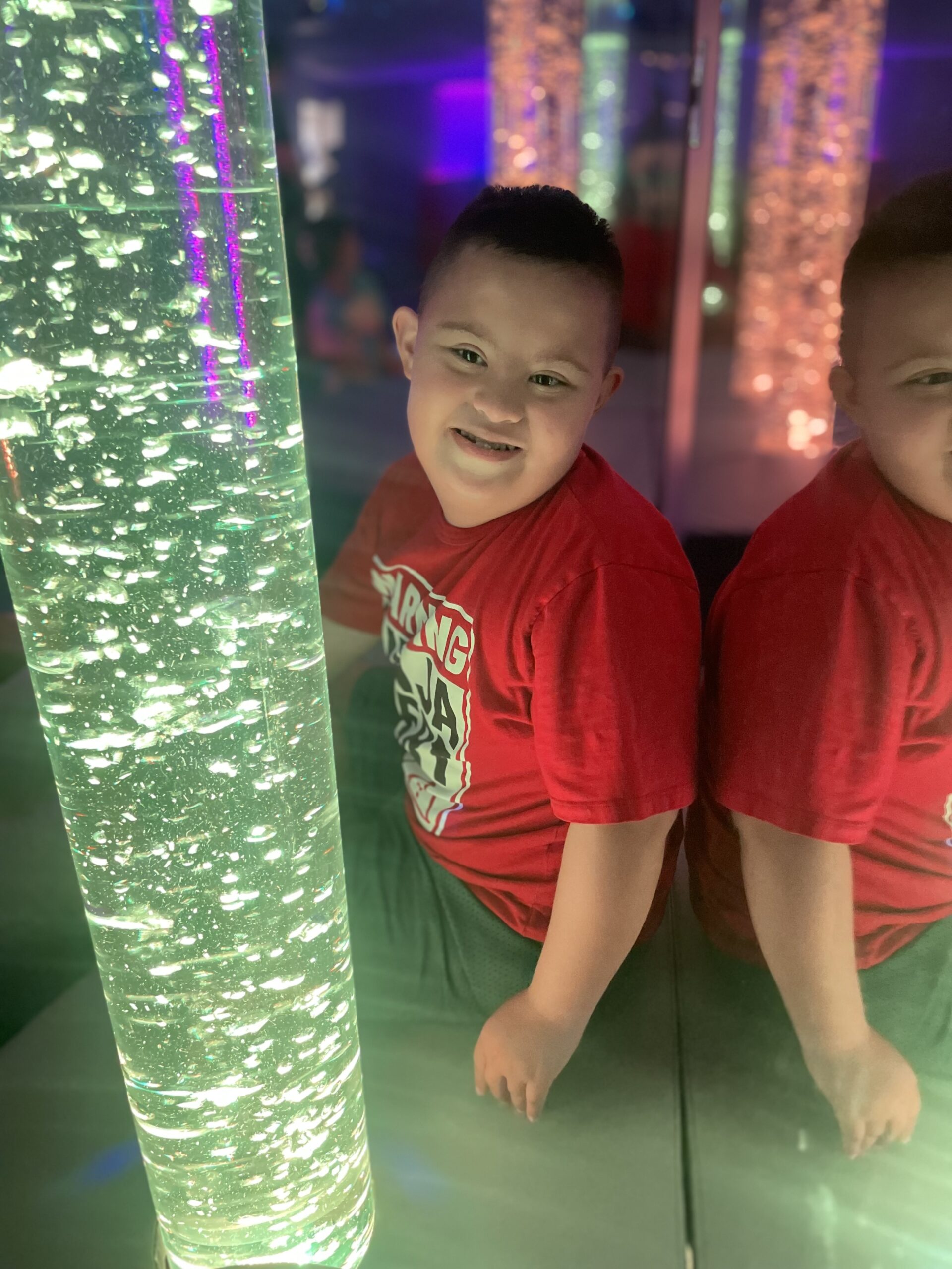 Young boy next to water tube in Sensory Room